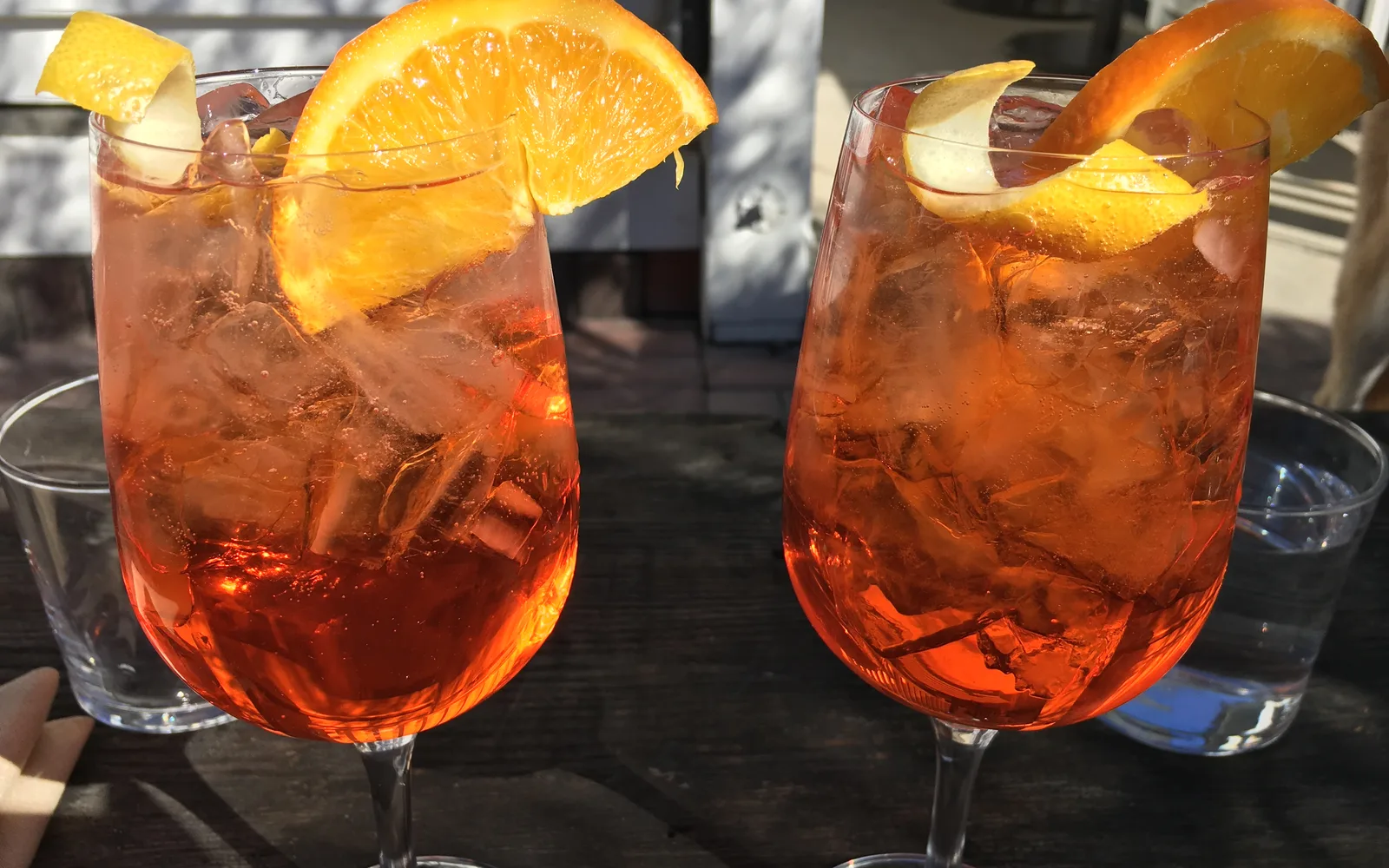两杯装满冰块和橙片的 Aperol Spritz 放在桌上