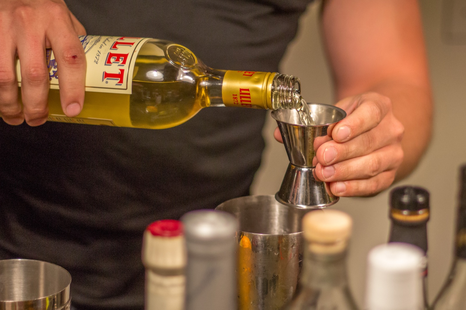 吧台上有人用金属 Jigger 量取酒液
