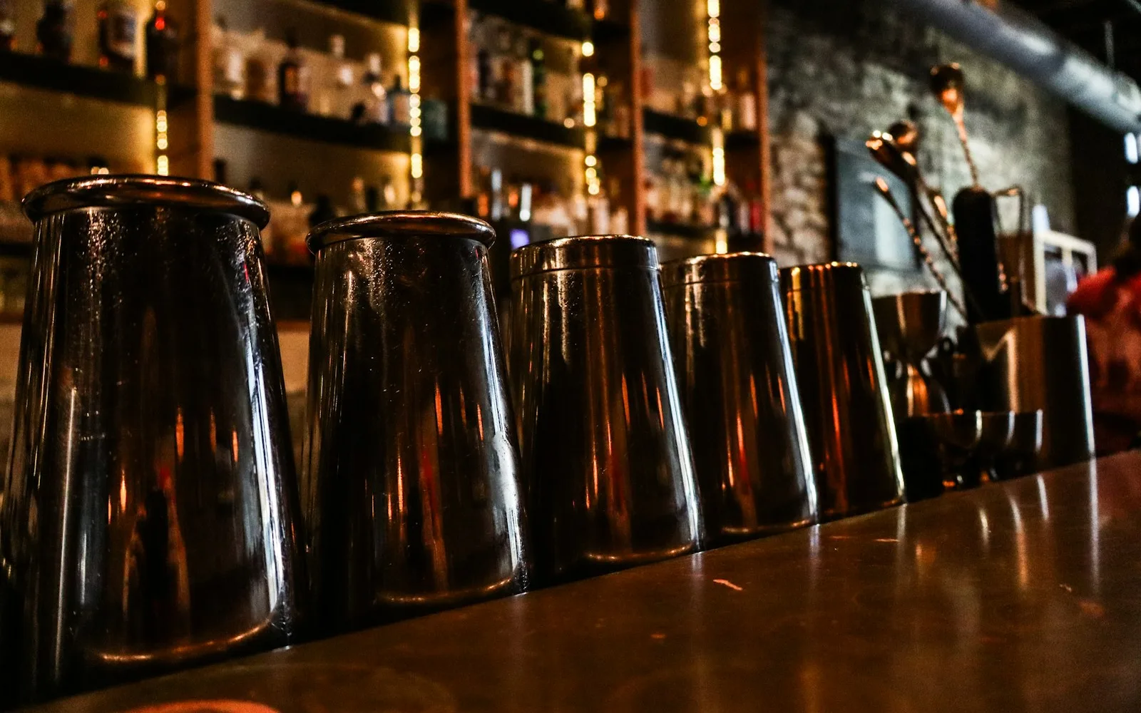 Metal cocktail shakers and bar tools arranged on a counter