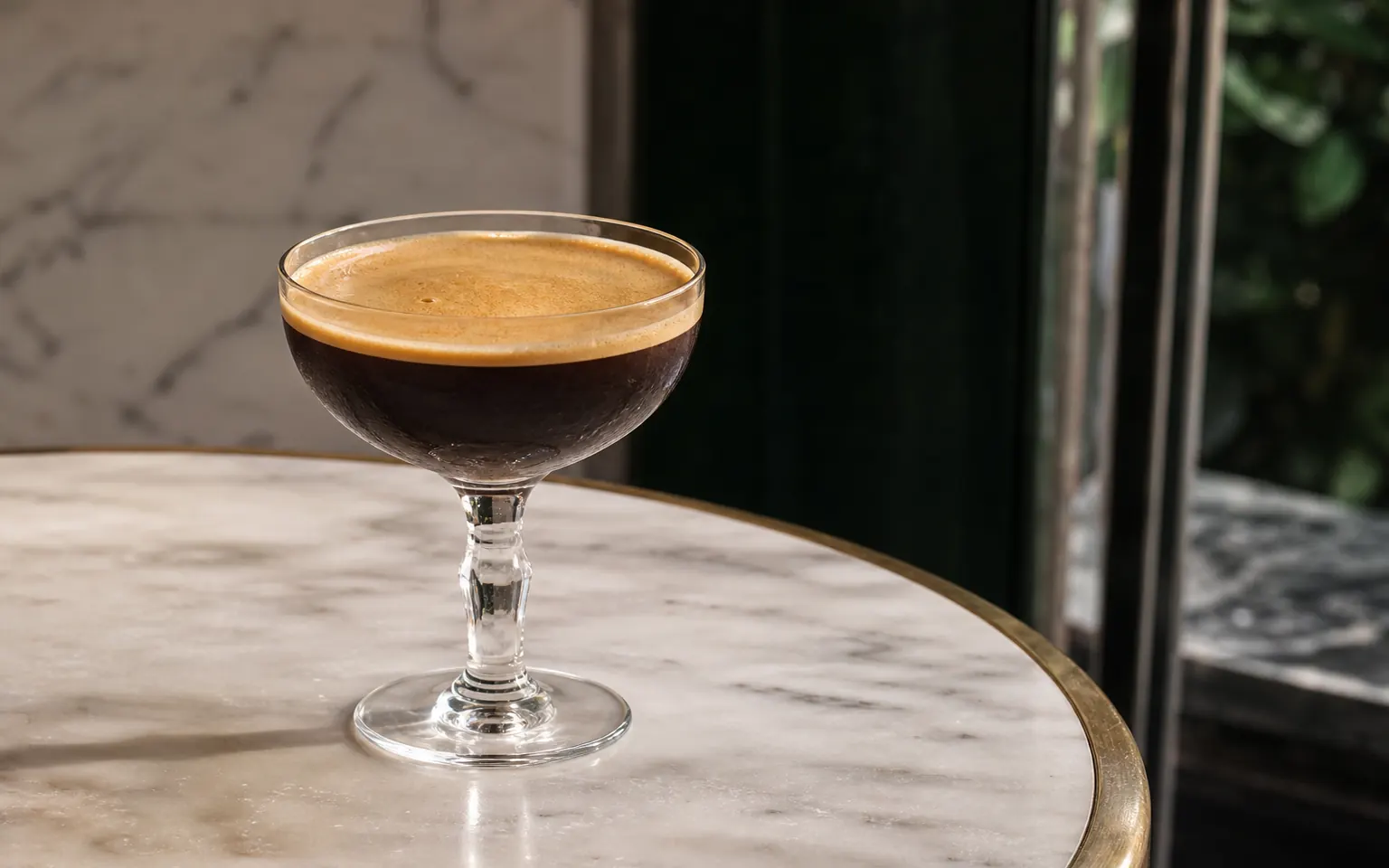 A small stemmed glass of Shakerato with fine tan coffee foam