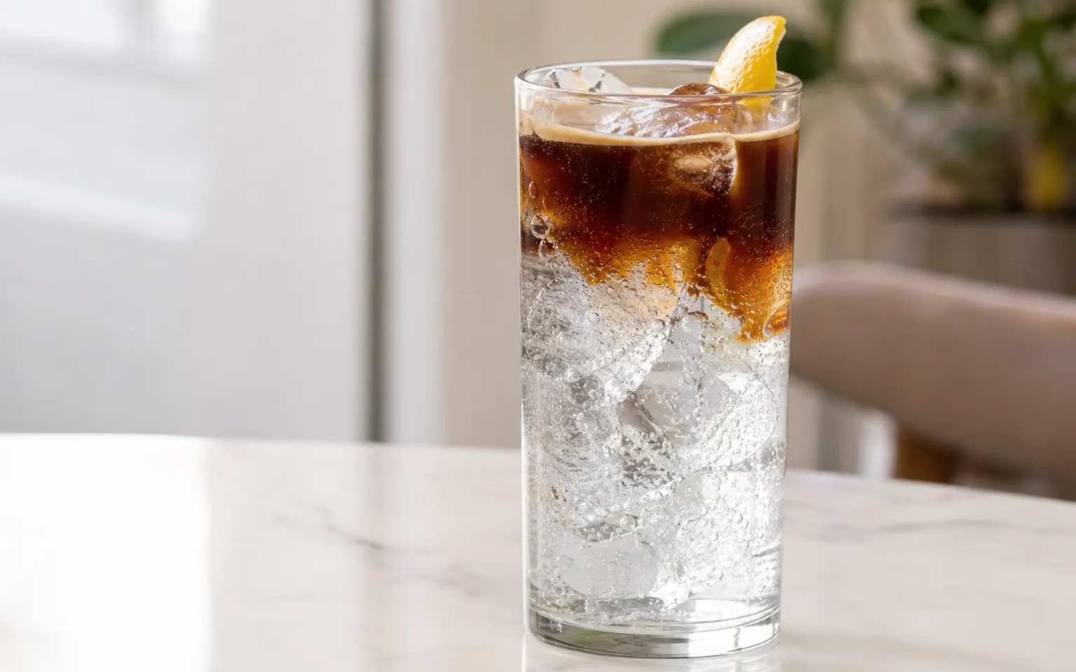 Dark coffee layered over clear sparkling water and ice