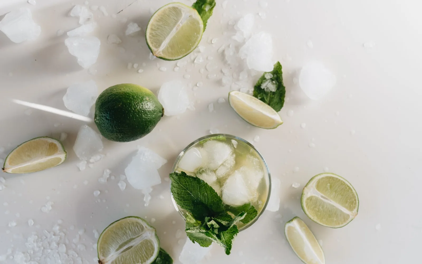 浅色背景上放着青柠、薄荷和冰块的 Mojito 风格饮品
